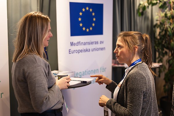 Två kvinnor som står och pratar med varandra.