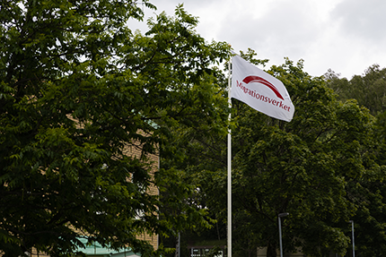Flagga med Migrationsverkets logotyp.
