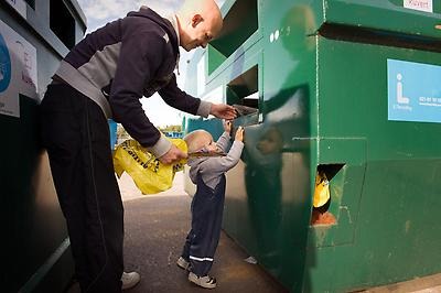 A man recycles together with a child.