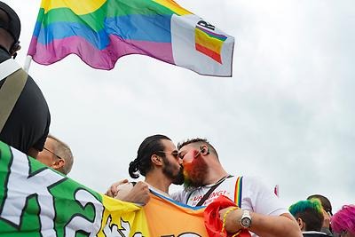Prideflaggan och två män som kysser varandra