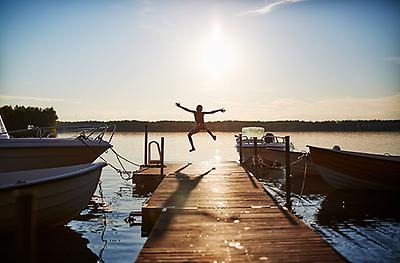 Un enfant saute dans l’eau d’un ponton au coucher du soleil.