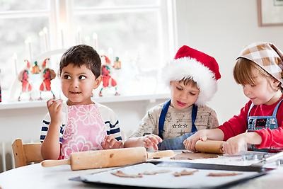 Three children bake gingerbread cookies together.