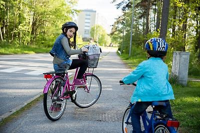 Two children wear helmets as they ride their bicycles.