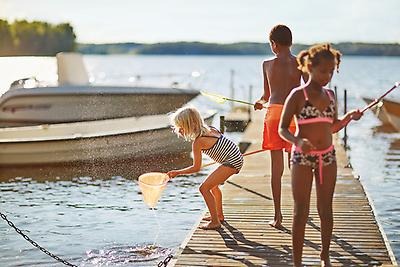 Three children in swimwear on a pier.